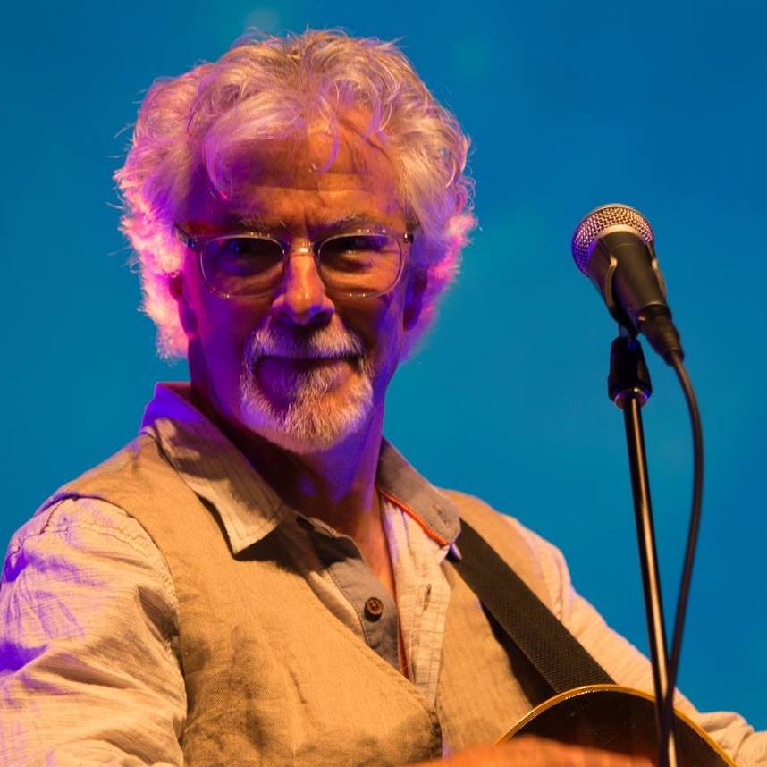 Bernie Simms with a guitar behind a microphone